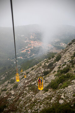 A scenic view from a cable car on a foggy mountain slope, overlooking a village. Elba Italy