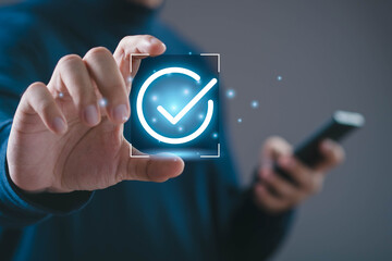 Businessman touching glowing check mark icon with smartphone representing approval process, verification success, secure confirmation, digital validation, quality assurance, and modern technology.