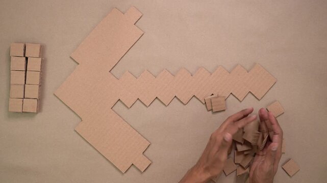 Top-down view of hands crafting cardboard pieces, displaying multiple hand-drawn patterns.