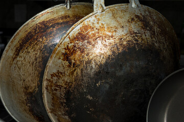 Close-up of a burnt frying pan bottom heavily blackened from prolonged and intensive use, showing...
