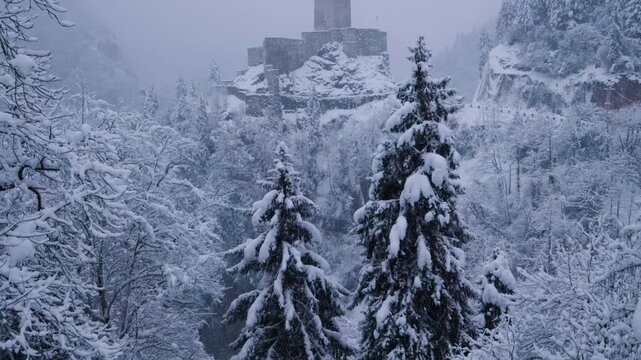 Snow-covered pine forest with Zilkale Castle rising in the background in Rize, Turkey. Atmospheric winter scenery with fog and mountains, ideal for travel, nature, history, and cinematic landscape con