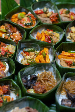 Traditional Indonesian dishes served in banana leaf bowls arranged in rows. Authentic Southeast Asian cuisine with eco-friendly packaging, ideal for food culture, catering, and sustainability concepts