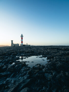 Coastal Lighthouse Reflected on Volcanic Rock Landscape