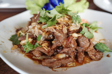 A close-up view of stir-fried meat topped with abundant crispy fried garlic and fresh coriander...