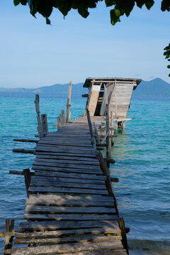 Rustic wooden pier leading to toilet hut over turquoise sea