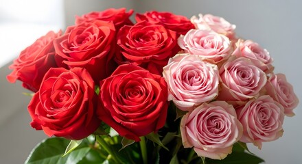 A bouquet of red and pink roses with green leaves arranged closely together in a beautiful floral display
