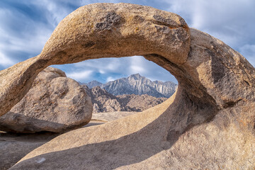 A large rock archway with a mountain in the background