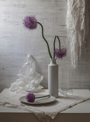 Still life with flowering onions in a white vase on a light background
