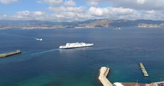 Aerial view of a ferry boat crossing the Strait of Messina. The Sicilian city is in the background. Panorama from Villa San Giovanni, in the province of Reggio Calabria, Italy.