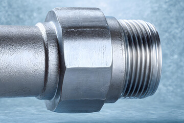 Close view of a metal pipe fitting showing threads and connector details for plumbing work