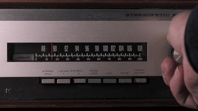 Person searching radio station frequency on vintage fm tuner. Close