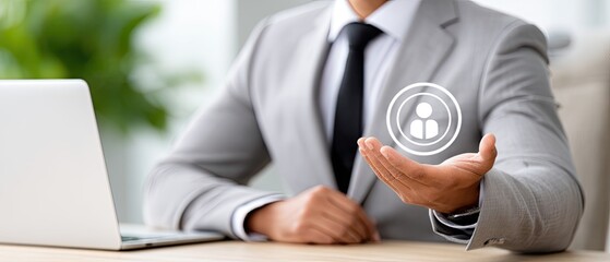 Businessman holds virtual icon of people network while using laptop in office, emphasizing teamwork and human resources