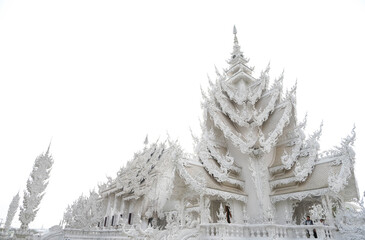 Low angle view of Wat Rong Khun against a white sky.