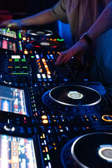 Obraz premium Professional DJ mixing tracks on advanced controller with colorful lights