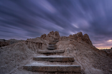 Long exposure of dark storm clouds passing over rocky steps leading out of a gorge in Nevada 