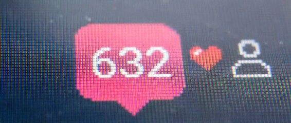 Social media notification icons for likes and followers with a numerical counter on a digital display, shown in an extreme close-up macro shot revealing the screen's pixel grid