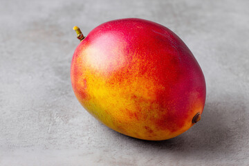 Fresh Whole Ripe Mango with Vibrant Golden-Red Skin on Neutral Surface