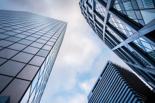 Modern corporate architecture skyscraper with glass facade in paris city looking upward into wide sky for business finance district background