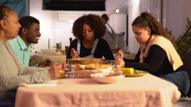 Happy african family having fun eating dinner together at house terrace - Parents, son and daughter's - Social gathering, lifestyle and healthy food concept