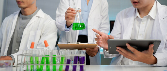 Diverse team of scientists in lab coats collaborating, analyzing data on tablets, surrounded by laboratory equipment, chemical structures