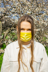 Young woman wearing protective face mask standing outdoors during pandemic