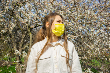 Young woman wearing protective face mask standing outdoors during pandemic