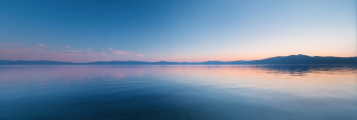 Tranquil sunset over calm lake and majestic mountain range horizon