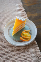 Delicious orange cake decorated with fresh orange slices on a textured tablecloth.
