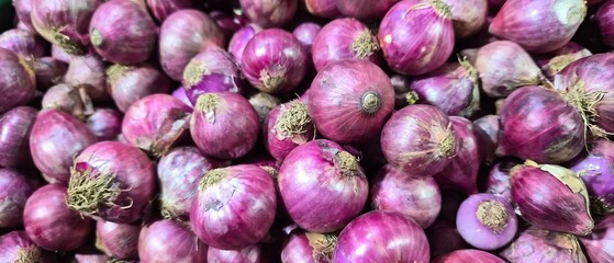 Fresh raw red shallots heap in traditional market. Organic purple onion bulbs background. High quality agricultural produce for culinary and spice ingredient.
