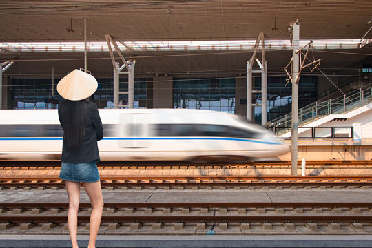 A  Chinese woman woman watching a high speed train wearing a conical hat and a denim miniskirt - High-speed train of China railway from Luoyang in Beijing, China