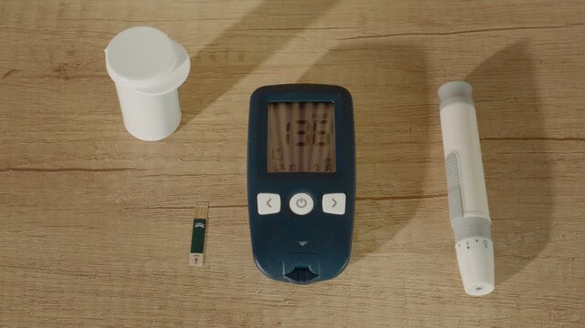 A glucometer displays a reading of 136 mg dL on a wooden table. This indicates a high blood sugar level. The setting includes test strips and a lancing device.