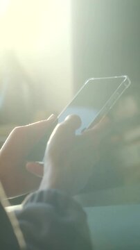 Close up hands person holding smartphone, scrolling through social media feed with thumb in brightly lit environment, showing modern communication, connection. Hands scrolling on smartphone screen