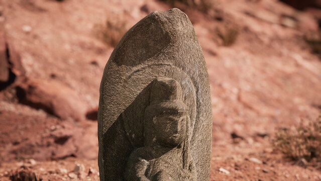 A weathered stone carving depicts a figure, surrounded by arid terrain. Sunlight casts shadows, highlighting details of this ancient work, rich in history and culture.