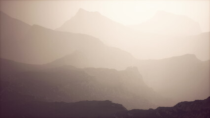 Obraz premium A serene landscape of layered mountains emerges under soft evening light, with mist swirling around the peaks, creating a tranquil mood in natures embrace.