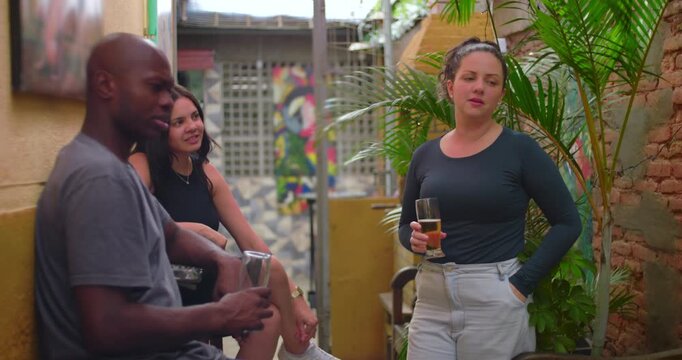 Friends standing together outdoors holding drinks sharing casual conversation and attentive listening in relaxed social pause