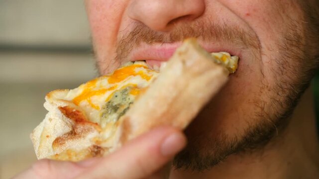 Close up bearded man mouth eating cheesy pizza slice, biting, chewing with great enjoyment, showing pleasure of fast food. Concept of having lunch or dinner. Man eating tasty pizza slice with appetite