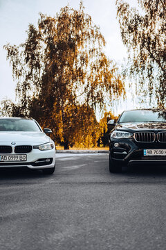 Vinnytsia; Ukraine; July 30, 2020: White BMW in the foreground and black in the back in the parking lot near the park