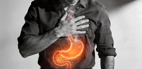 Man experiencing burning stomach and acid reflux with glowing stomach representing painful digestive issues and heartburn