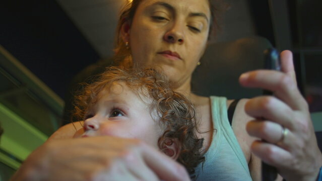 Mother sets phone aside and lifts baby closer during train ride, shifting attention from screen to child in quiet moment of reconnection