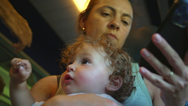 Mother sets phone aside and lifts baby closer during train ride, shifting attention from screen to child in quiet moment of reconnection