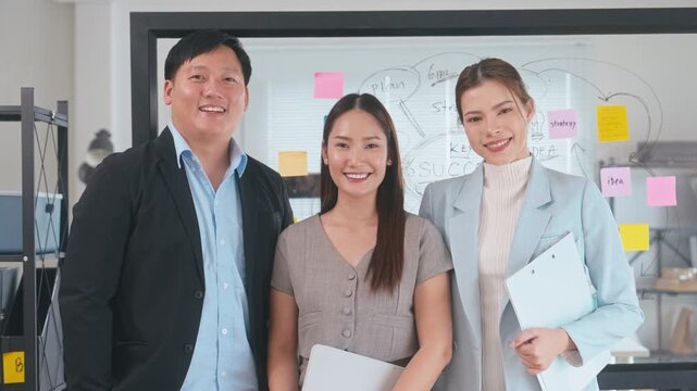 Close up Portrait of three confident Asian business professionals standing together in a corporate office. Professional team representing leadership, success, and unity in a modern workspace