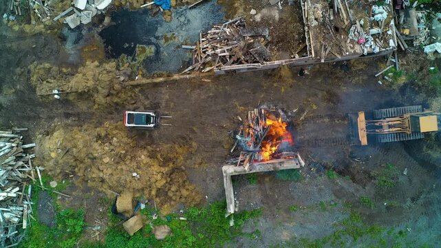Aerial view looking down at a large fire being contained by heavy equipment and people on a construction site.