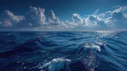 Vast dark blue ocean with rolling waves under a dramatic cloudy sky, sunlight breaking through