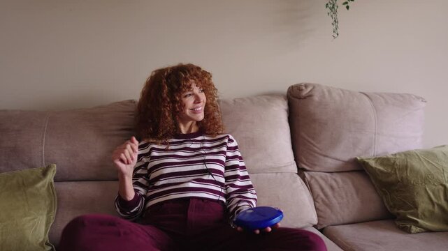 Happy redhead woman listening music on a vintage cd player