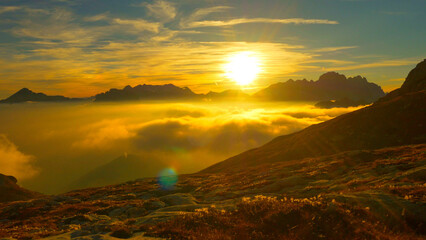 Fototapeta premium AERIAL: Flying over the empty meadow with patches of snow at golden sunset.