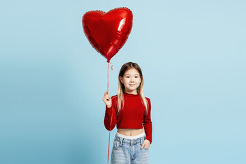 Young girl holding a red heart balloon, celebrating love and joy