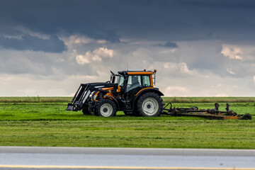 Wheel tractor with lawn mower working by the road