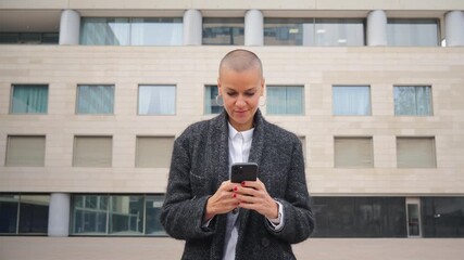A focused lady is using her smartphone while standing outdoors, demonstrating the effectiveness of mobile applications in a professional context. She appears engaged and purposeful with her device.