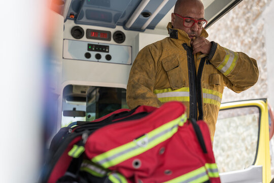 Firefighter wearing protective gear inside emergency ambulance getting ready for rescue