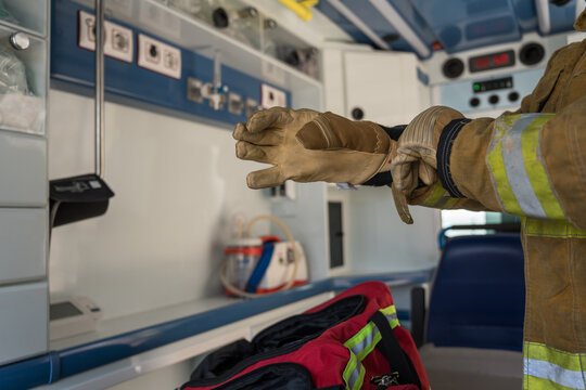 Firefighter wearing protective gloves inside ambulance getting ready for emergency